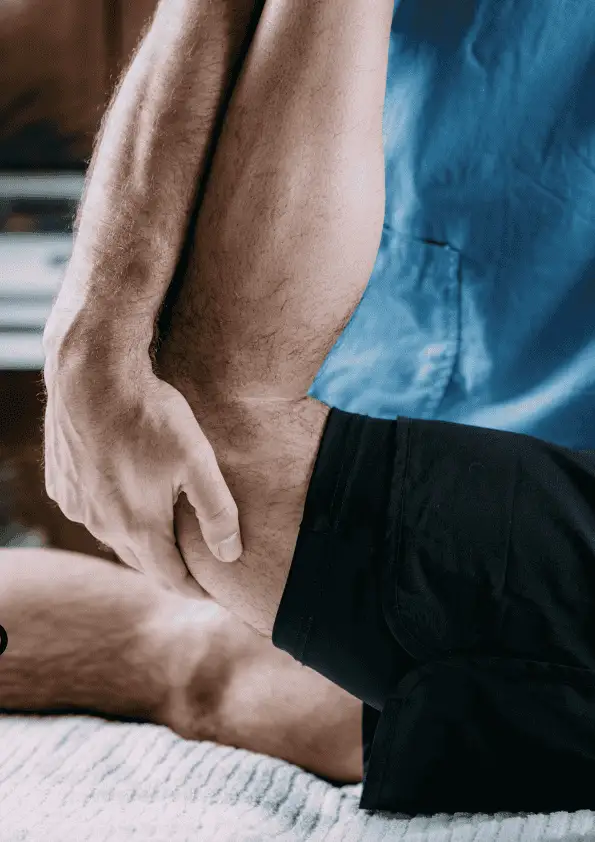 A close-up of a person receiving a leg stretch from a therapist during a sports massage session.